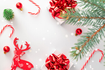 Gift boxes background. White gift box with red ribbon, New Year balls and sparkling lights in Christmas composition on white for greeting card. Winter festive composition with copy space.