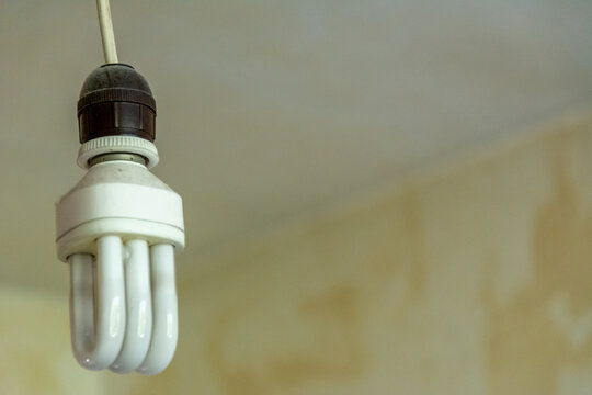 Electrical CFL lamp on barebone socket in old an grunge style room