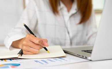 Business women keep records of statistics and company profits In the office to prepare for tomorrow morning meetings, business ideas and note-taking.