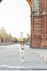 Young woman traveling and exploring the city with a vintage camera. Female solo traveler visiting Barcelona to take pictures. Cute lifestyle outfit