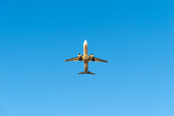 Airplane flying, view from below with blue sky in background