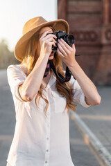 Beautiful woman in explorer outfit traveling and taking pictures with vintage camera. Freelance photographer working outdoors in Barcelona.