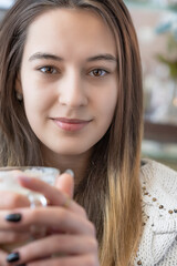 Portrait of a young beautiful girl in a cafe with a cup of coffee, close-up.