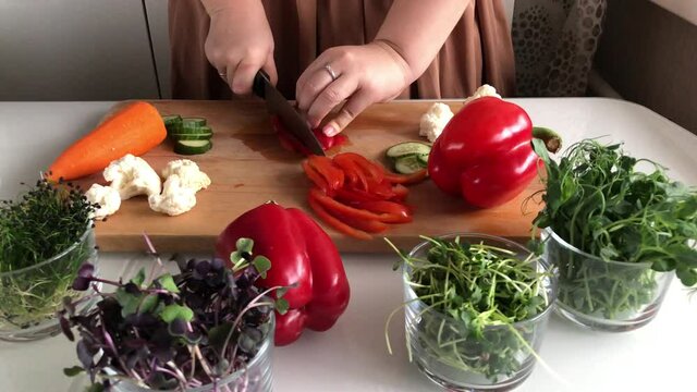 A woman cuts peppers for a delicious healthy vegetable salad