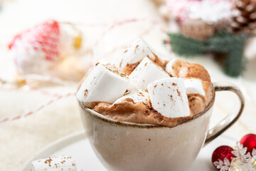 Hot cocoa or hot chocolate with marshmallows in a ceramic Cup surrounded by gingerbread, Christmas tree branches and ornaments on a brown wooden table. Christmas or new year's composition