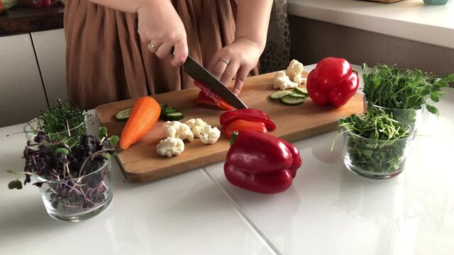 A woman cuts peppers for a delicious healthy vegetable salad