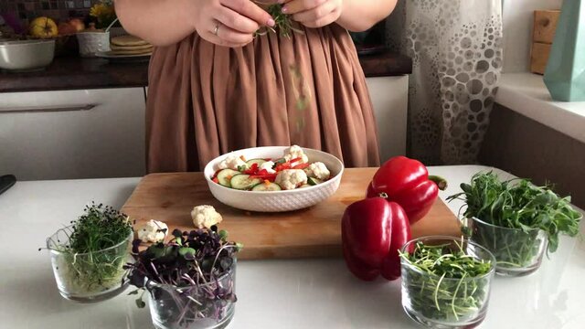 Woman adds sprouts to a healthy vegetable salad