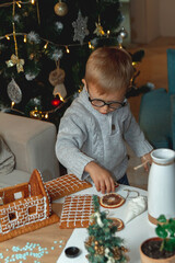 Little boy decorates christmas gingerbread house