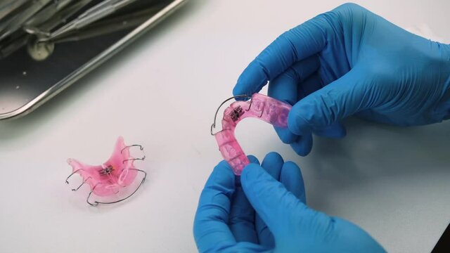 The dentist is demonstrating unscrewing a dental extension device to increase the area of the tooth, removable braces or retainer for children with crooked teeth.