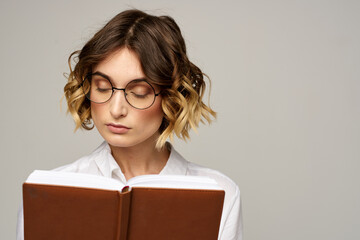 Business woman with notepad and glasses on a light background hairstyle success emotions