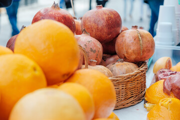 ripe orange oranges and red pomegranates lie in a basket on the display case.