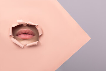 Beautiful girl plump young lips on a beige background close-up. Cosmetology injection augmentation...