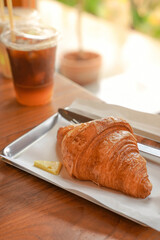 Delicious breakfast with fresh croissants and coffee served with butter on wooden table.