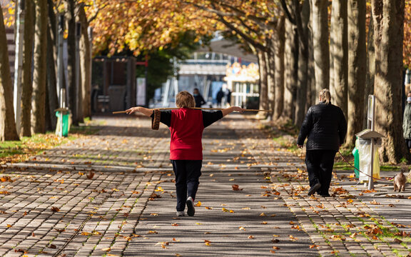 Parisian people walking in the Parc de la Villette in Paris during the second national lockdown declared in France. A woman is doing stretching exercises with a stick while another is walking her dog.