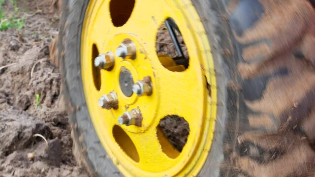 Yellow wheel of a tractor on a farm field. The motoblock is farm. Tractor wheel tire. Truck tire. Car repair. Farm equipment. Agricultural mechanization. Horticultural mechanization. Vehicle.