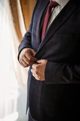 Stylish man groom buttoning a button on his jacket