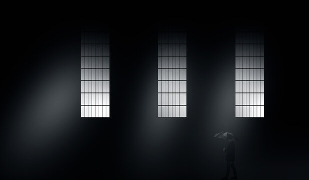 Dark theme shot of a man walking with an umbrella under big windows with light coming out of them with some fog.