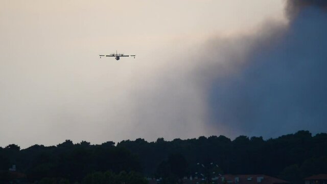 Two amphibious water bombers dropping water on Anglet Chiberta Forest fire. In France, 30 July, 2020.