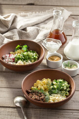 Ingredients for the traditional Russian cold soup okroshka Cucumbers, eggs, dill, onions, sour cream on wooden table