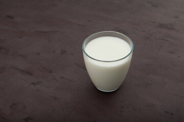 Ayran or kefir in a glass on brown background. Fermented milk ayran. Milk diet for weight loss. Selective focus, copy space