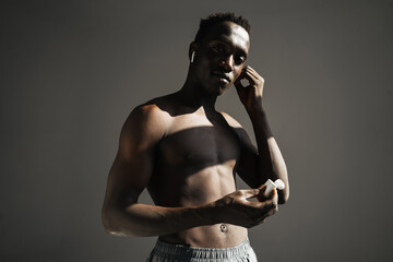 Pleased african american sportsman using earphones while working out