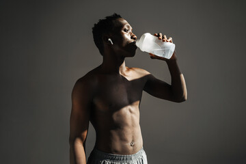 African american sportsman using earphones while drinking water