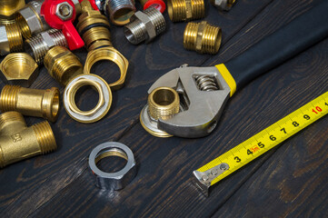 A set of brass fittings and an adjustable wrench on vintage planks. Plumber master work environment