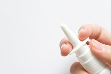 Hand holding nasal spray on white background