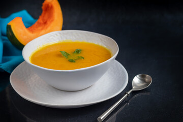 Fresh pumpkin cream soup with sour cream. Autumn lunch concept. On a wooden background. A dietary, healthy dish.