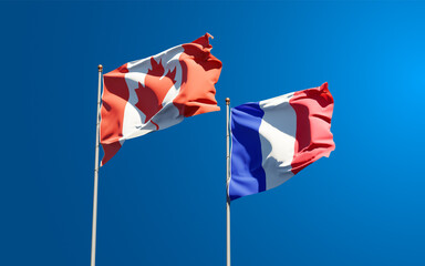 Beautiful national state flags of Canada and France together at the sky background. 3D artwork concept.