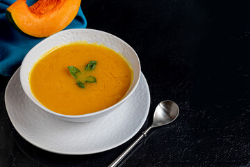 Fresh pumpkin cream soup with sour cream. Autumn lunch concept. On a wooden background. A dietary, healthy dish.