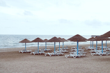 Tumbonas y sombrillas de paja en la playa Olimp en Rumania. Playa vacía un nublado y frío día de verano.