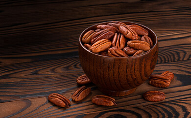 Pecan nuts in bowl on wooden background
