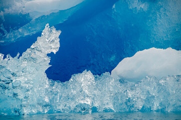 Transparent ice of an iceberg with bluish ice in the background