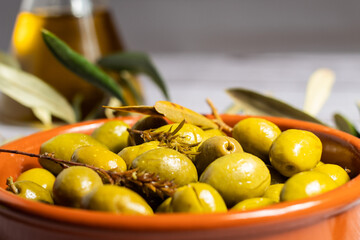 Un primer plano de aceitunas y fondo difuminado con la aceitera