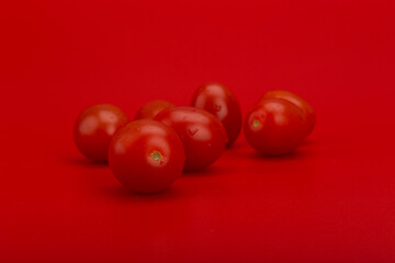 Bunch of cherry tomatoes with drops of water on red background. Concept of healthy eating, dieting, cooking or vegan food