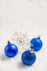 Blue Christmas balls and snowflake in the snow with copy space and selective focus.