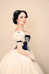 A beautiful elegant dark haired woman in a historic 1867 coronation dress on a white background looks at the camera