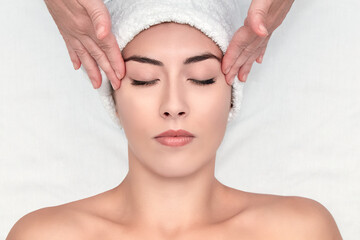 Spa treatment. Facial massage. Massage of the client's forehead.