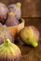 Top view of figs, with more background in wooden bowl, with selective focus, on wooden background, in vertical