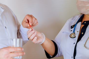 Doctor holding in gives the patient a red pill