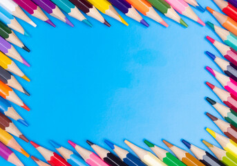 Color pencils on blue background, top view with space for text or creativity.Frame