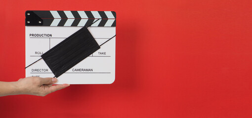 Hand is hold clapper board or movie slate with black face mask. it use in video production and...