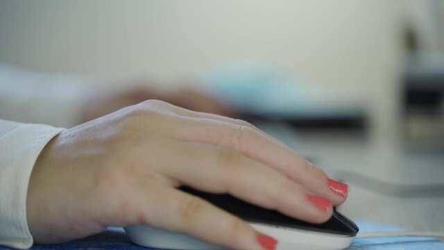 woman with orange painted nails typing on a keyboard then moving the mouse by clicking