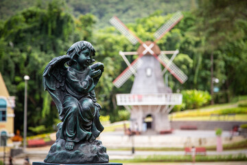 statue of an angel foreground and blur wind turbines background in the park