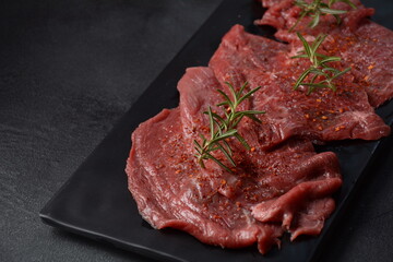 Raw beef steaks with spices and rosemary.