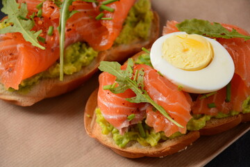 Whole grain bread sandwich with avocado paste and salmon, egg, and arugula leaves