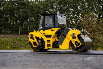 Obraz na płótnie Canvas Asphalt road roller with heavy vibration roller compactor press new hot asphalt on the roadway on a road construction site. Heavy Vibration roller at asphalt pavement working. Repairing.