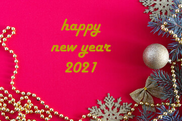 happy new year 2021 inscription, christmas frame made of toys and fir branches on a red background with beads and bows