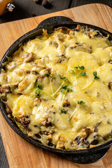 Baked mushrooms with beef and cheese. Serving food in a restaurant in a cast iron skillet on a board.